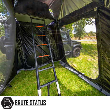 Black SUV with ARB Esperance 2.0 Rooftop Tent Annex Room, featuring mesh windows and telescoping ladder, set at a grassy campsite, branded “Brute Status”.
