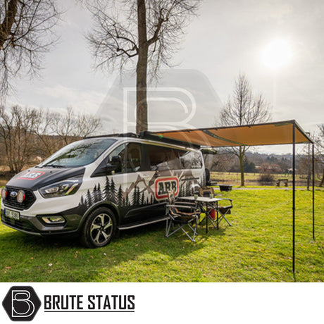 ARB Awning with Light Black Aluminium Case 3m x 2.5m on a camper-van in a field, showcasing easy setup and integrated lighting for outdoor comfort.
