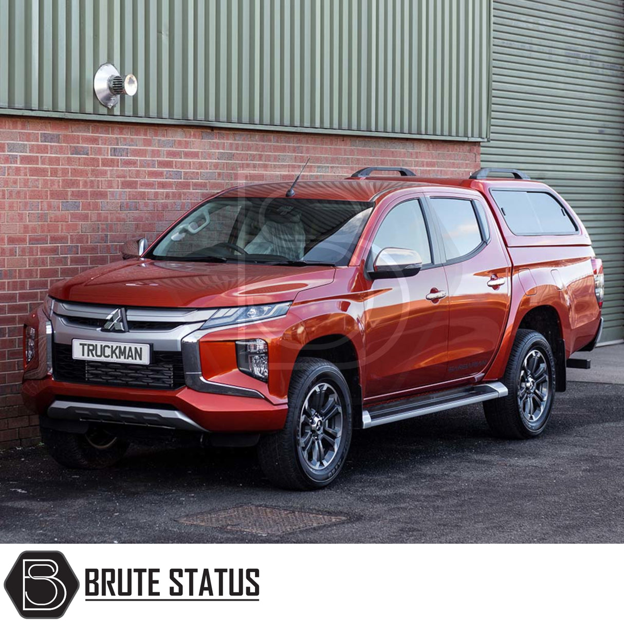 Red double-cab pickup with Truckman GLS Hardtop Canopy, featuring remote locking and tinted windows, parked against a brick and metal wall.