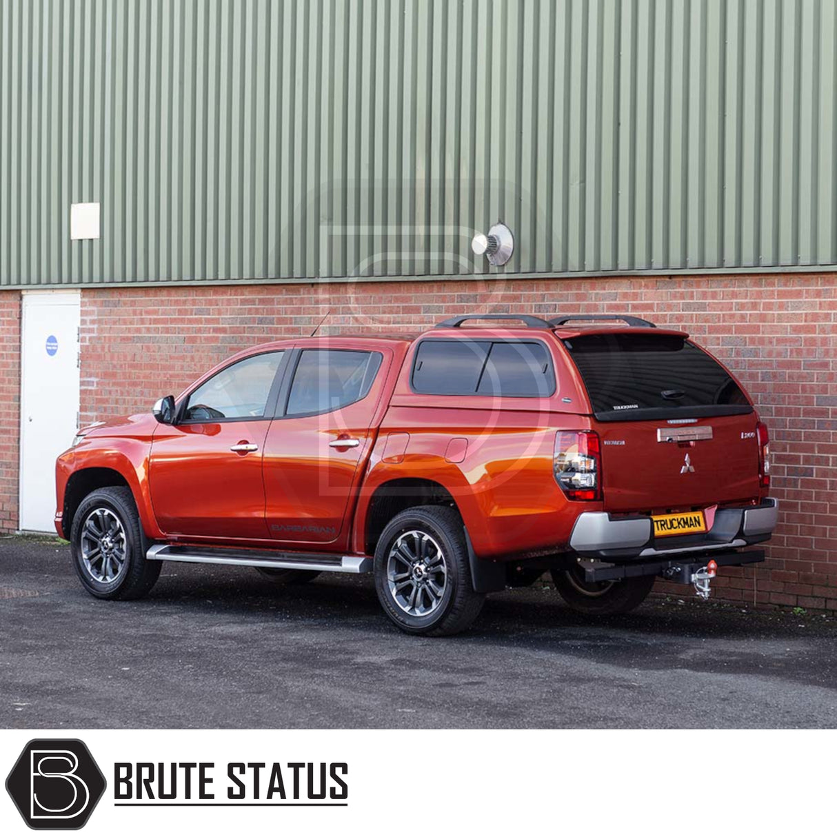 Red Mitsubishi L200 with Truckman GLS Hardtop Canopy, featuring remote locking, tinted windows, and alloy wheels, parked by industrial building, showcasing Brute Status aftermarket accessories.