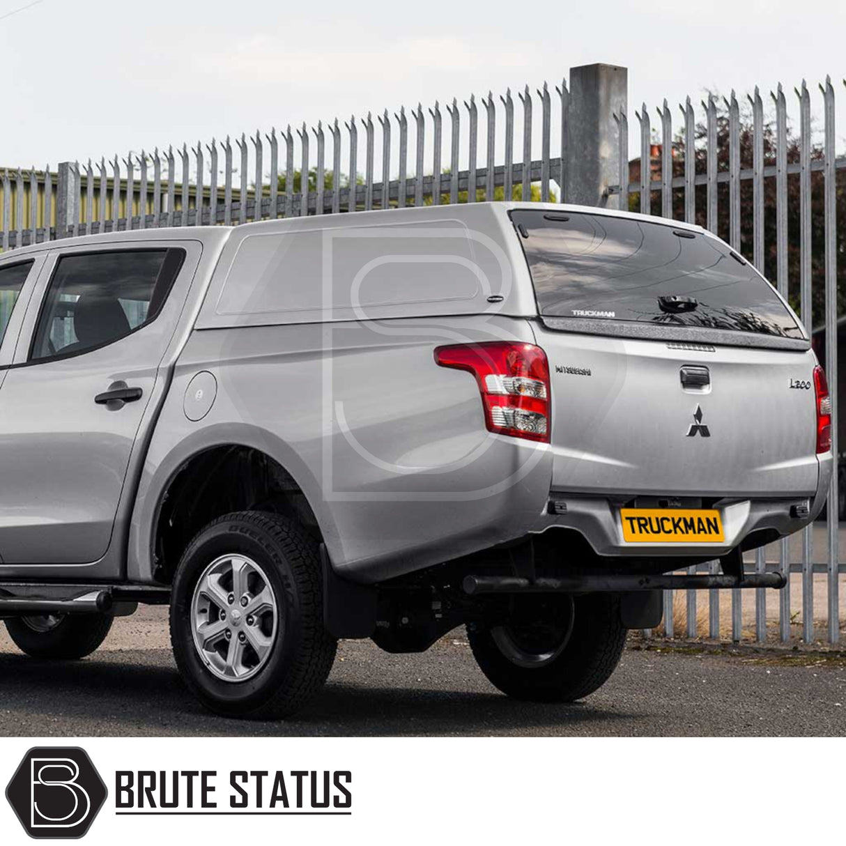 Silver Mitsubishi L200 with Truckman RS Hardtop Canopy, glazed rear window, remote locking, parked on tarmac, showcasing aftermarket accessory for enhanced security and versatility.