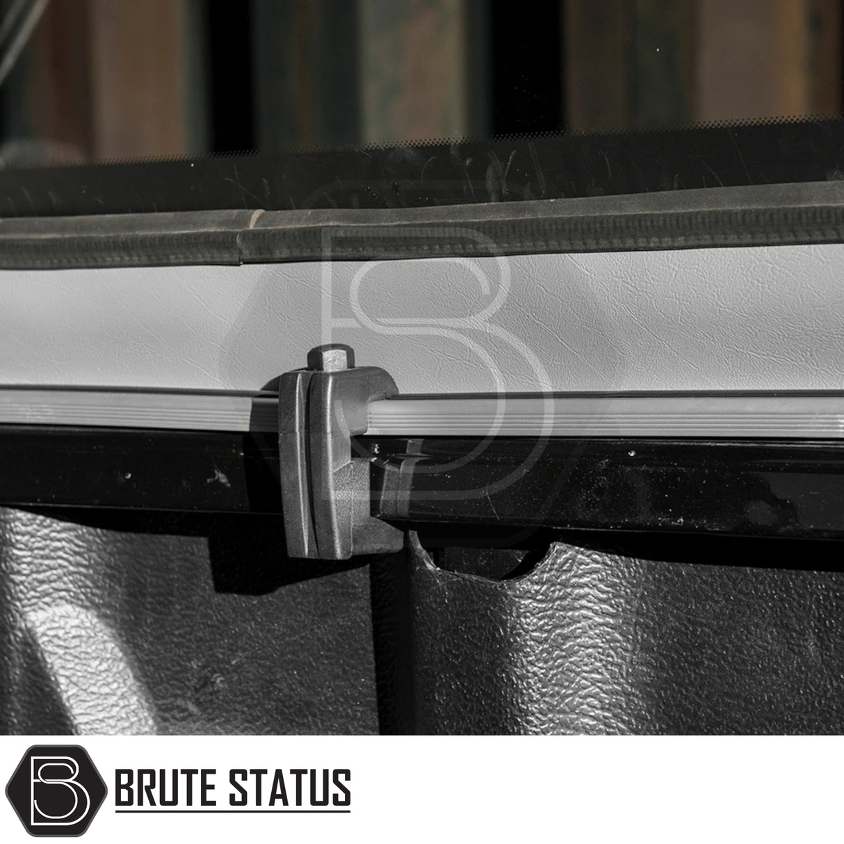 Close-up of a Truckman Grand Hardtop Canopy clamp mechanism gripping an aluminum rail on an Isuzu D-Max, featuring the Brute Status logo.
