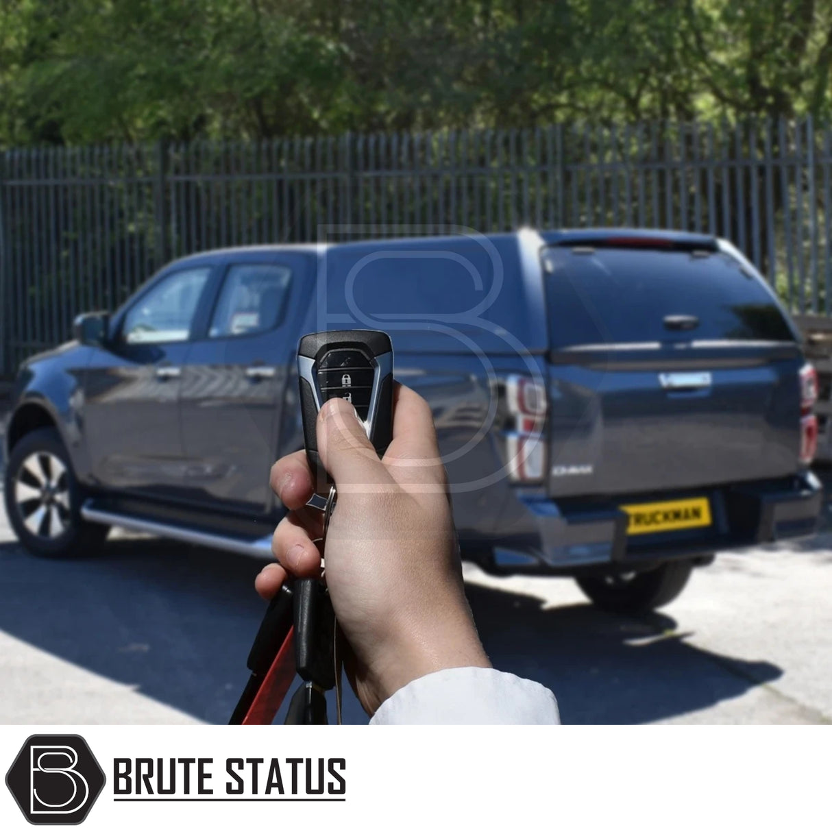 Hand holding remote key-fob pointed at parked grey Isuzu D-Max 2025+ Truckman RS Hardtop Canopy with solid rear window and remote locking, showcasing secure design.