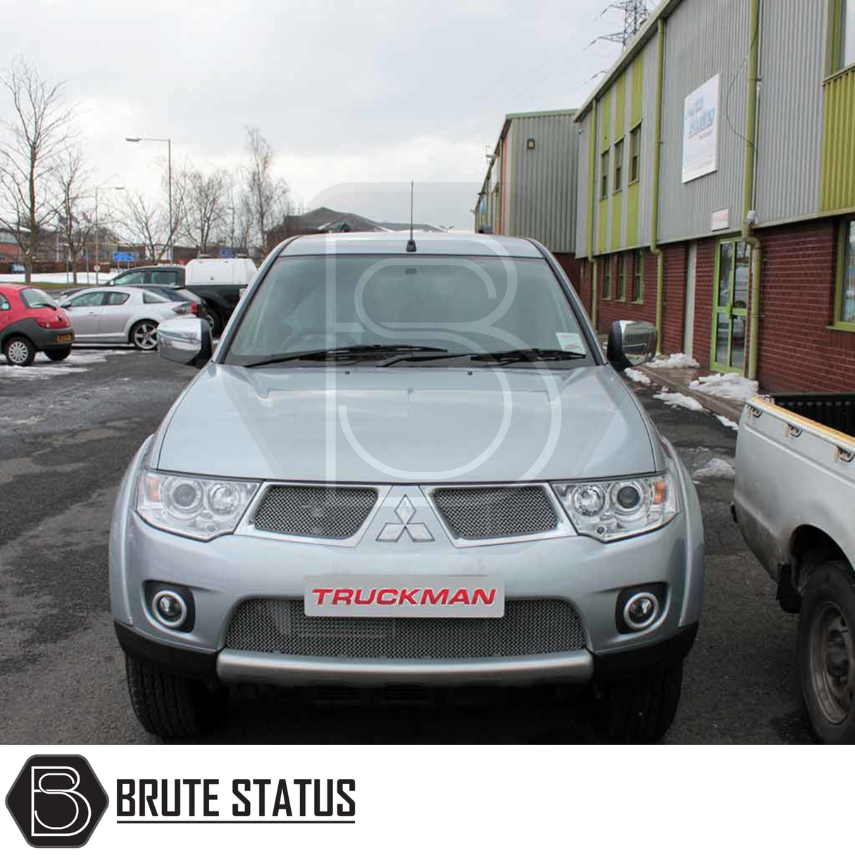 Silver Mitsubishi L200 with Truckman Grand Hardtop Canopy, featuring cab-high design and tinted pop-out windows, parked in an industrial lot.
