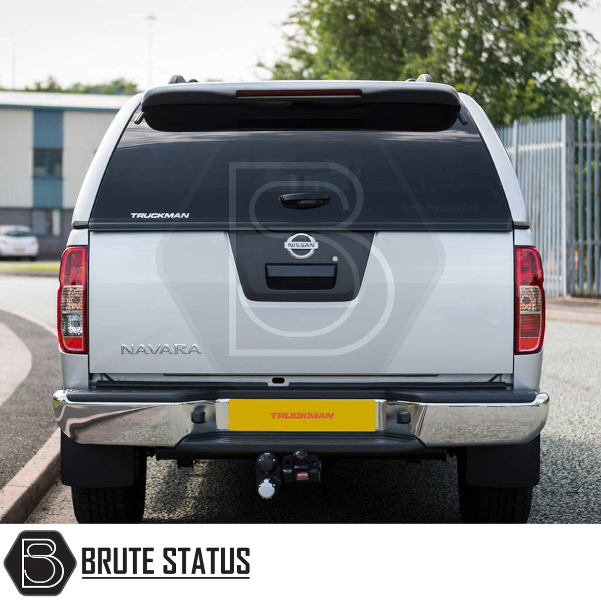 Nissan Navara 2005-2015 D40 Truckman GLS Hardtop Canopy - Rear view showcasing the tinted window, tow hitch, and Truckman logo, with industrial backdrop.