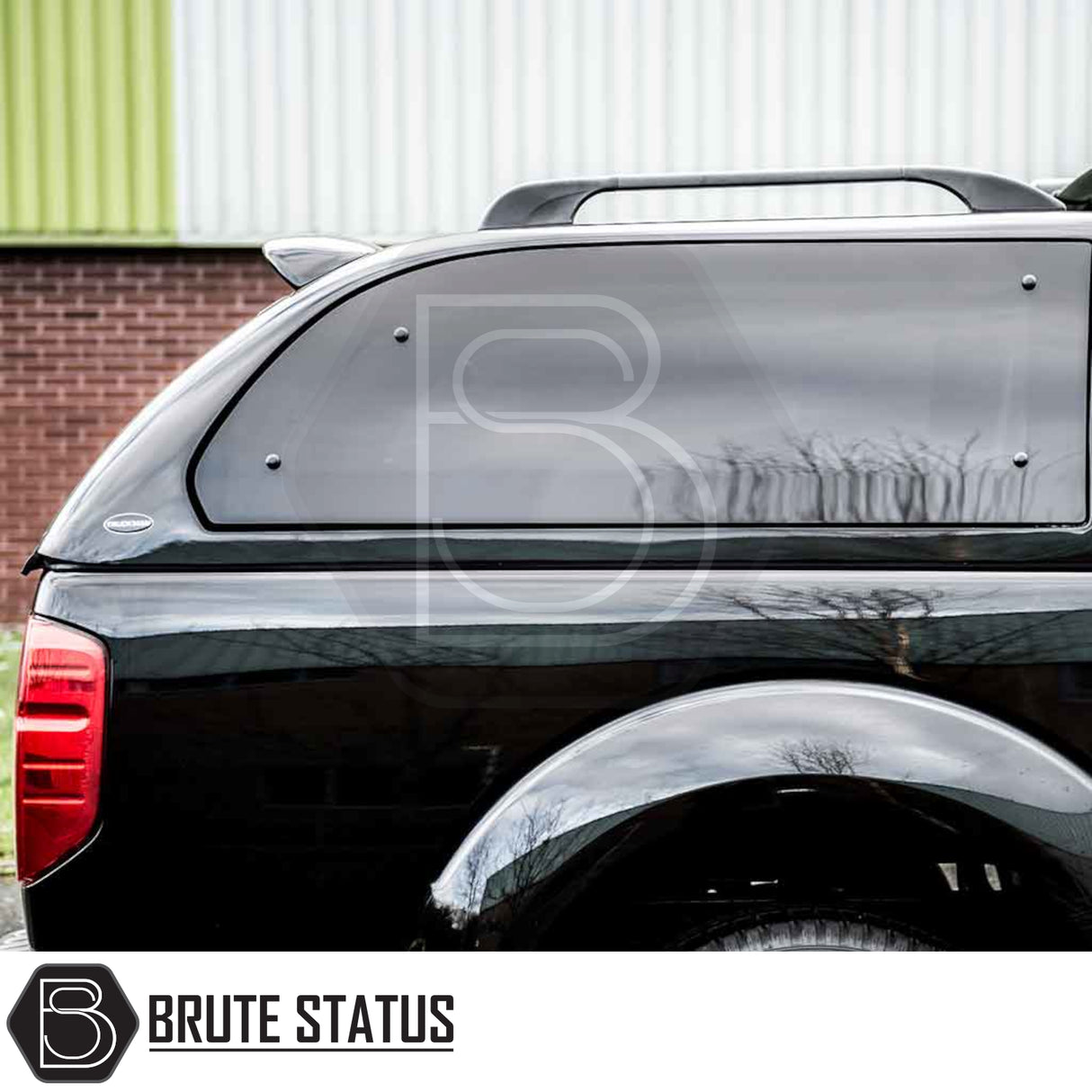 Side view of Nissan Navara 2005-2015 D40 Truckman Grand Hardtop Canopy, showcasing tinted windows, roof-rack rails, and Brute Status logo.