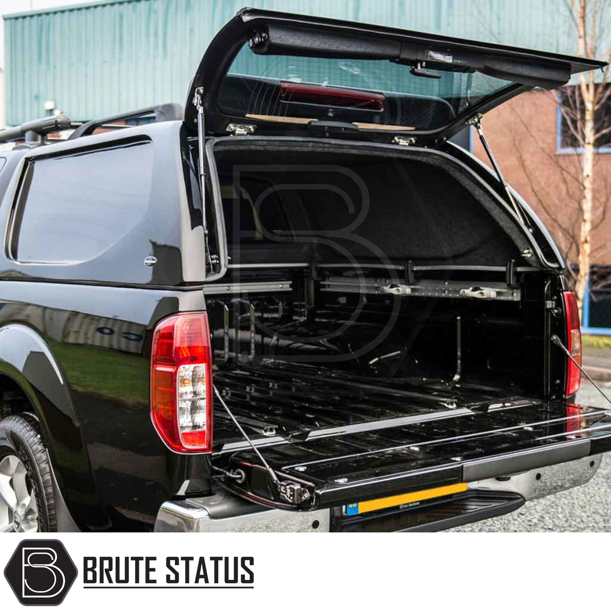Nissan Navara 2005-2015 D40 Truckman L-Series Hardtop Canopy with remote locking, shown on a black pickup truck, rear hatch open revealing empty truck bed.