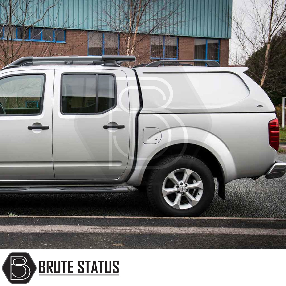 Side view of a Nissan Navara D40 with Truckman L-Series Hardtop Canopy, featuring remote locking, parked in front of an industrial building.