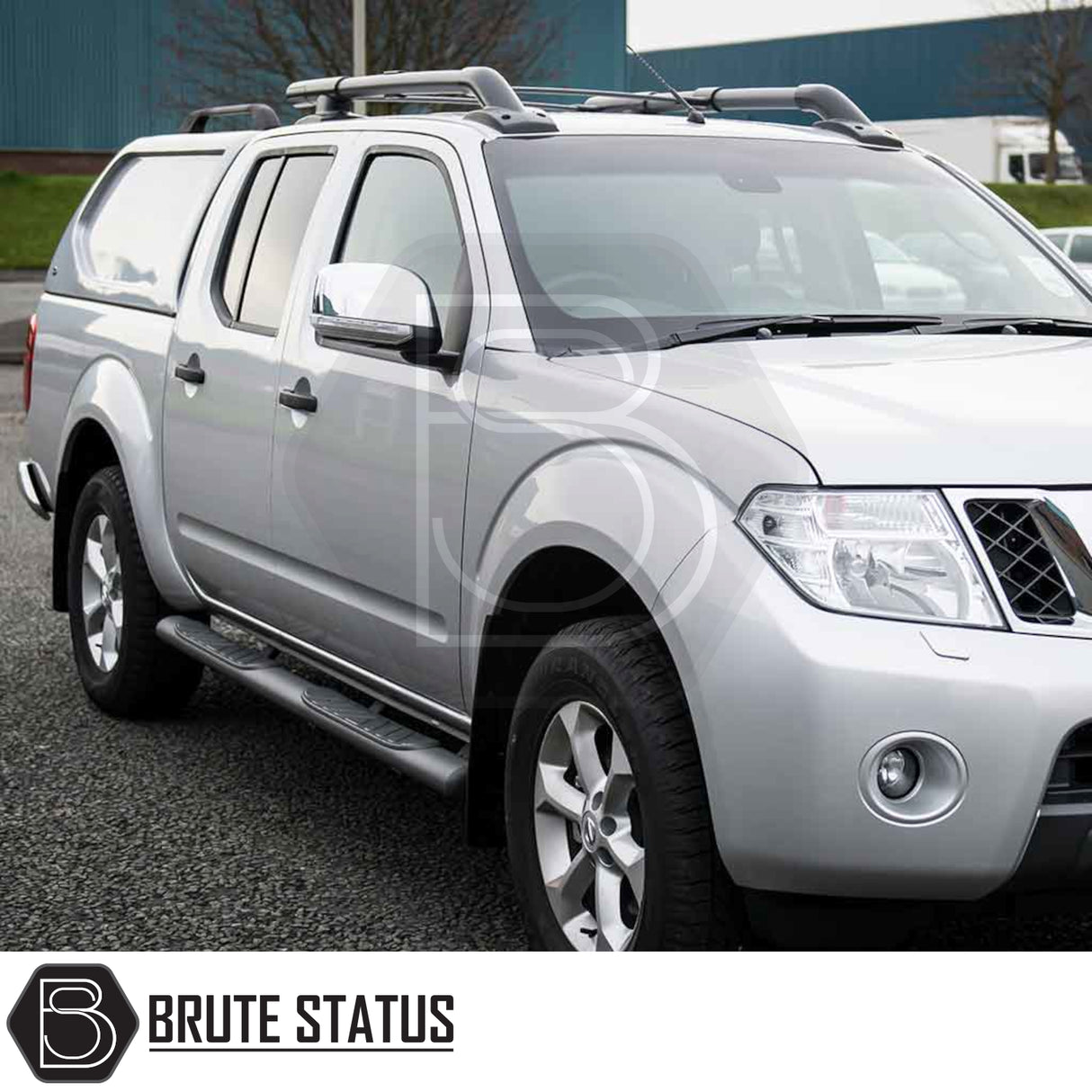 Nissan Navara 2005-2015 D40 with Truckman L-Series hardtop canopy, featuring aftermarket roof racks and Brute Status branding, parked on a paved surface.
