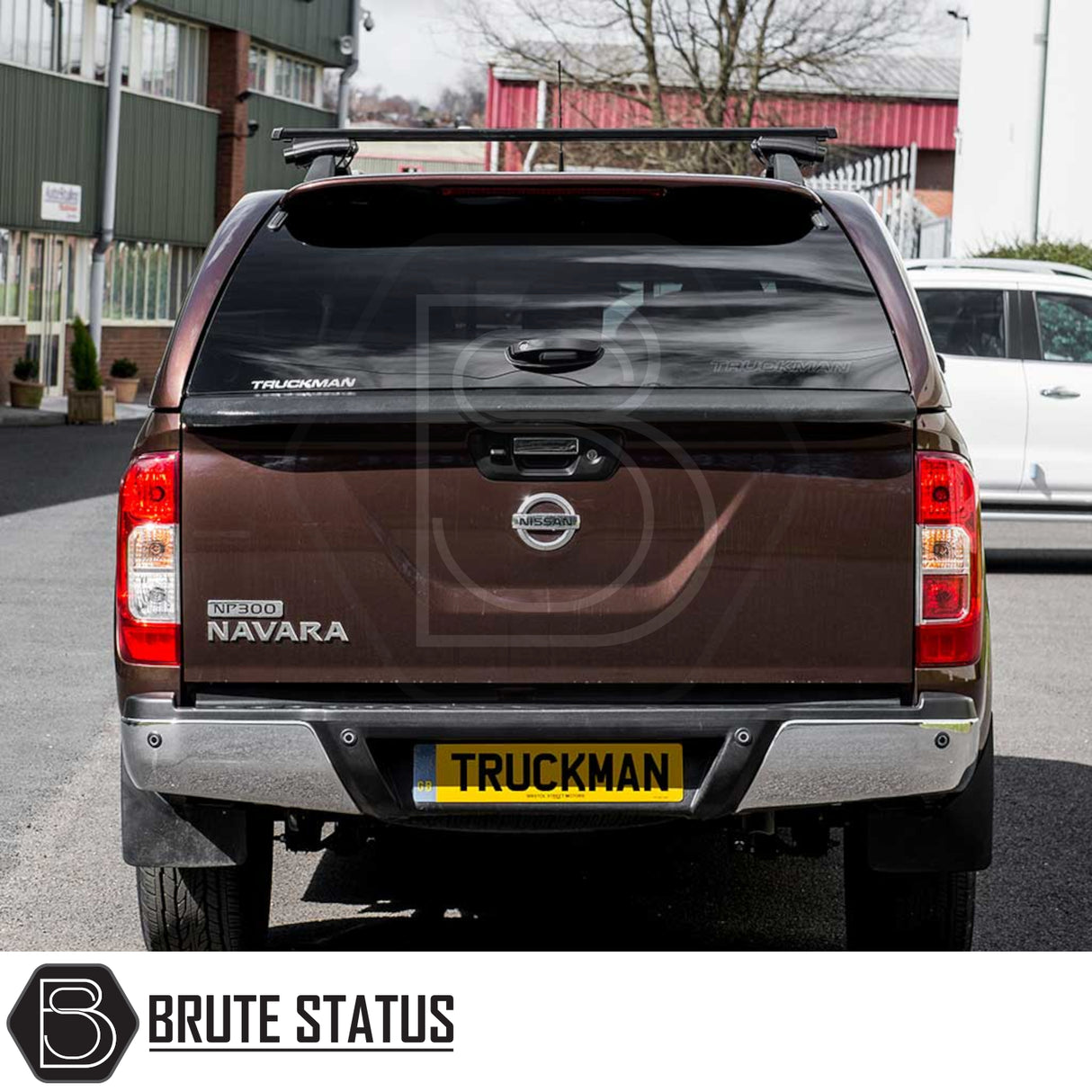 Nissan Navara 2015-2023 NP300 Truckman Grand Hardtop Canopy with branded rear view, featuring remote locking and roof-rack bars, parked in an industrial setting.