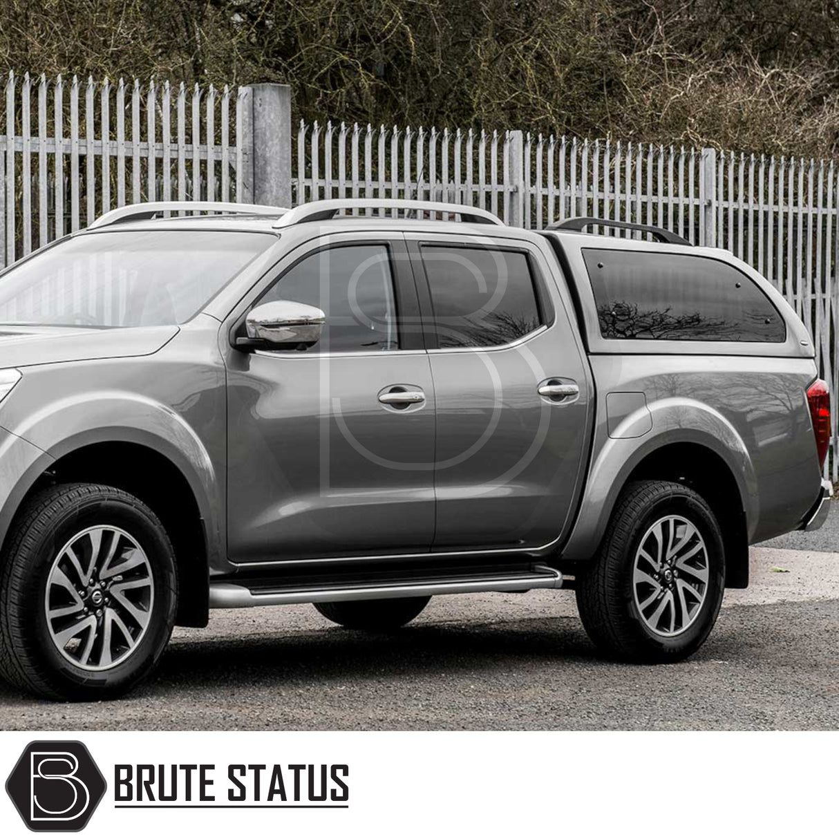Silver-grey Nissan Navara with Truckman Grand Hardtop Canopy featuring remote locking, cab-high design, and tinted windows, parked on gravel surface by Brute Status.