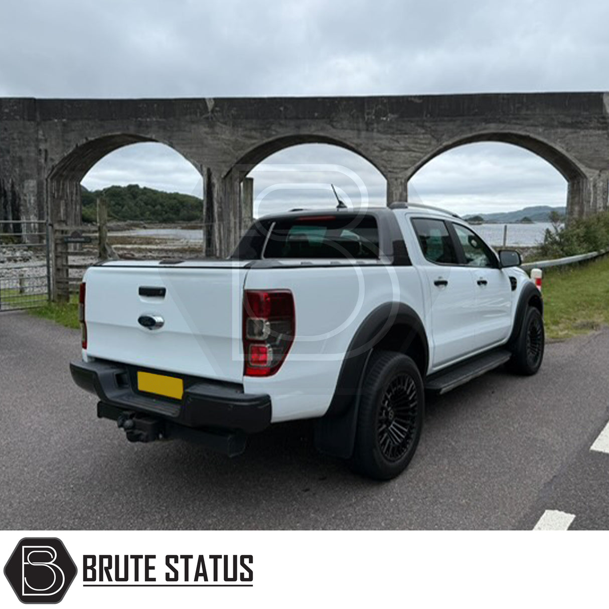 White double-cab pickup with Obsidian OB2 Wheels in Gloss Black, parked near a stone viaduct. Wheels feature 20x9.5 size, 6x139.7 PCD, visible on the truck.