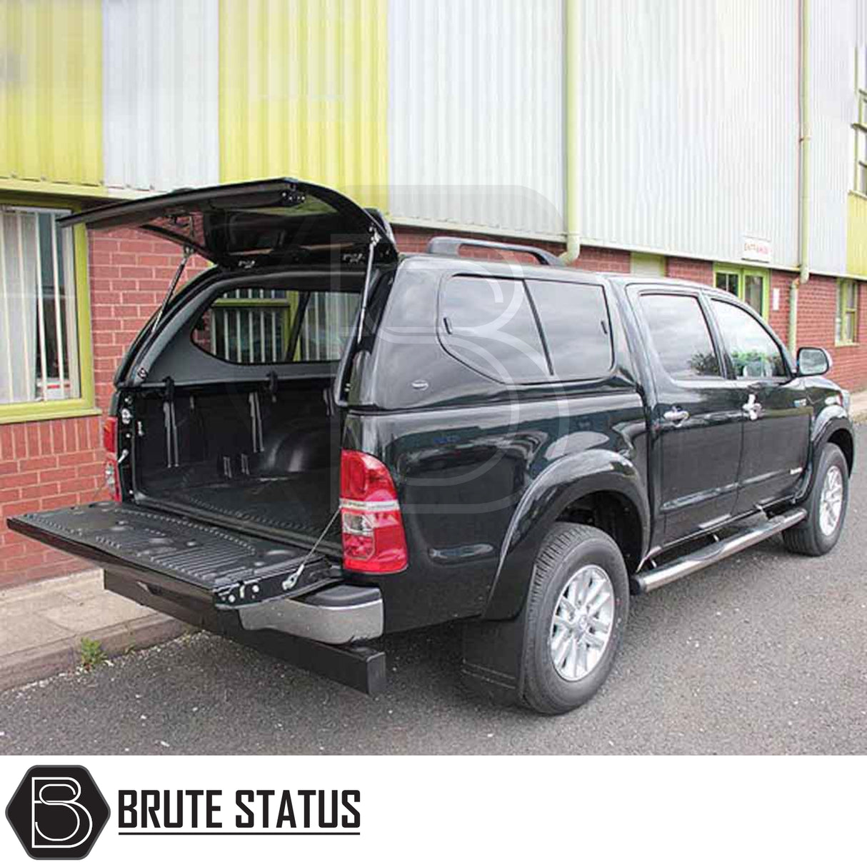 Toyota Hilux 2005-2016 MK6, MK7 Truckman GLS Hardtop Canopy with remote locking, open cargo area, parked by a warehouse, featuring Brute Status logo.