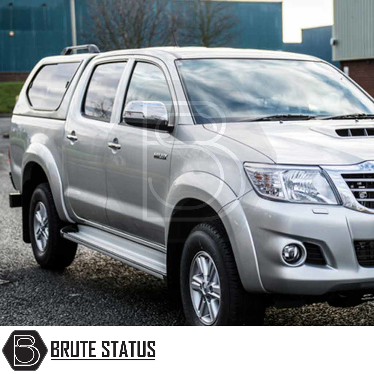 Silver Toyota Hilux 2005-2016 with Truckman GLS Hardtop Canopy featuring remote locking, parked in front of industrial buildings, showcasing secure sliding windows and sporty design.