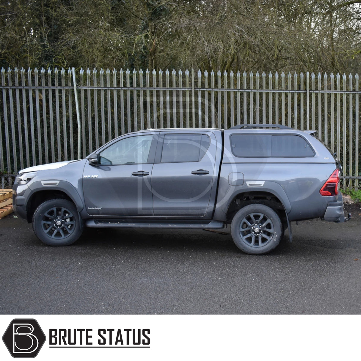 Toyota Hilux Invincible X with Truckman GLS Hardtop Canopy, featuring remote locking, tinted sliding windows, and sporty design, parked in front of a metal fence.
