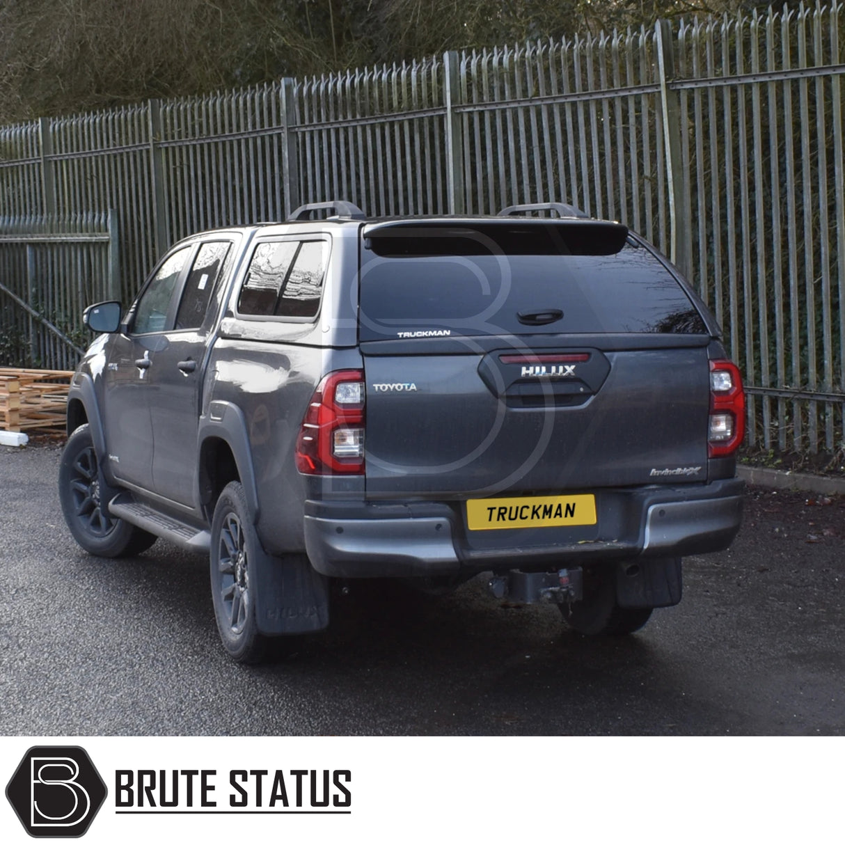 Toyota Hilux Invincible X 2016+ MK8, MK9 with Truckman GLS Hardtop Canopy, showcasing its sporty design and remote locking feature, parked beside a metal fence.