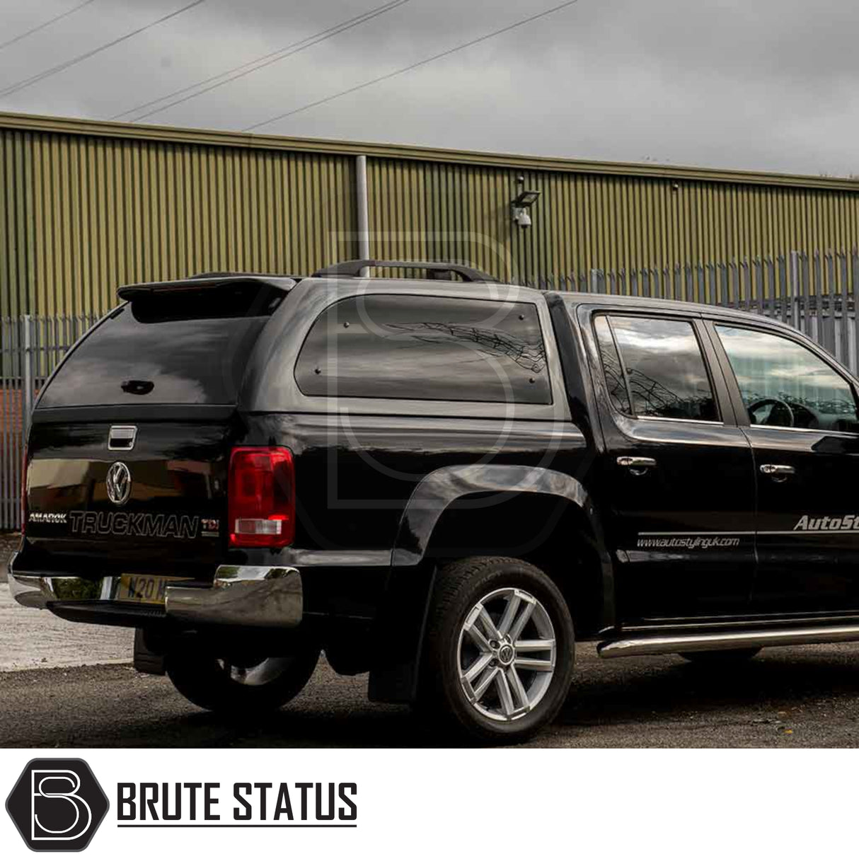 Volkswagen Amarok with Truckman Grand Hardtop Canopy, featuring remote locking and tinted windows, parked before an industrial warehouse.