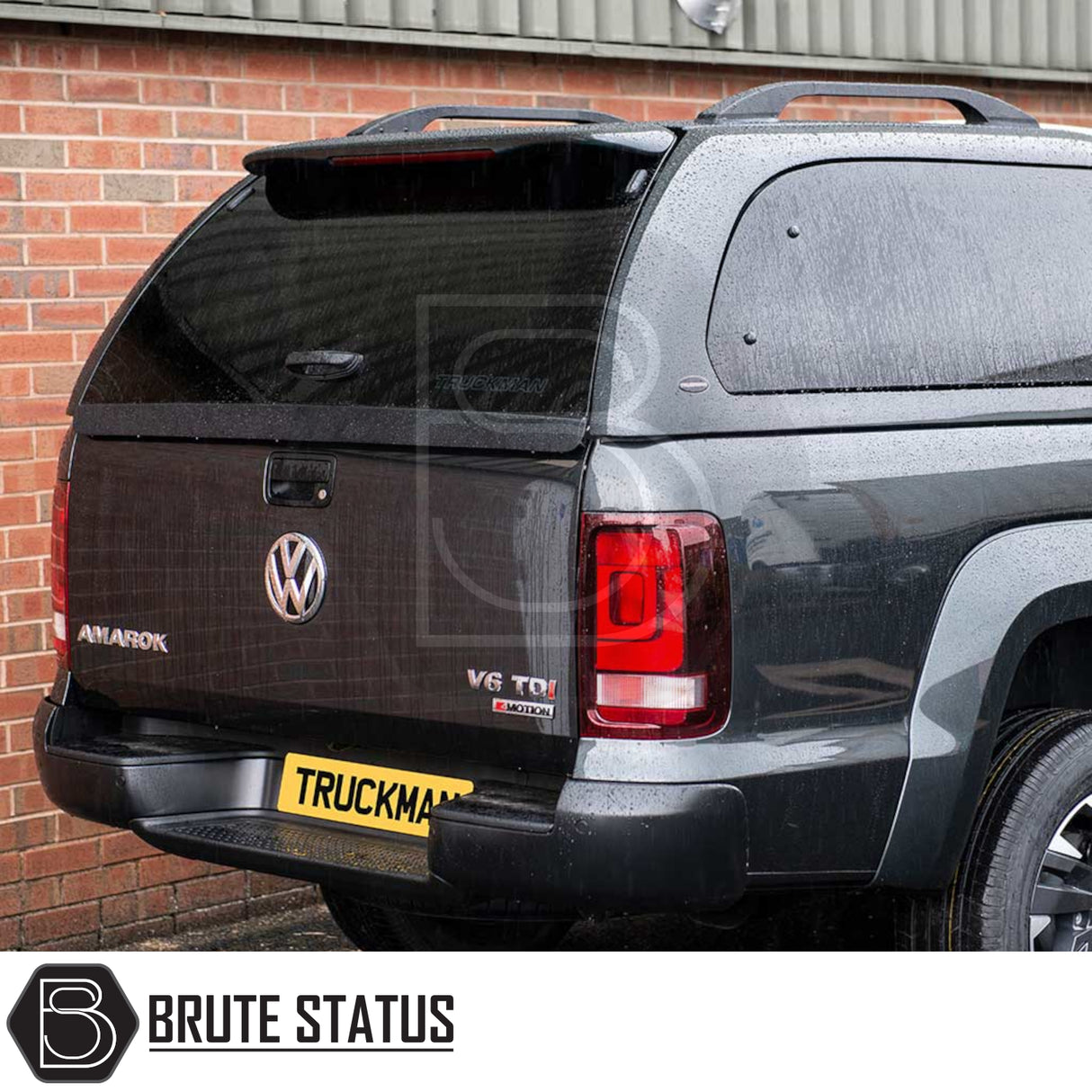 Rear view of a dark grey Volkswagen Amarok with a Truckman Grand Hardtop Canopy, featuring remote locking, tinted windows, and Brute Status branding.