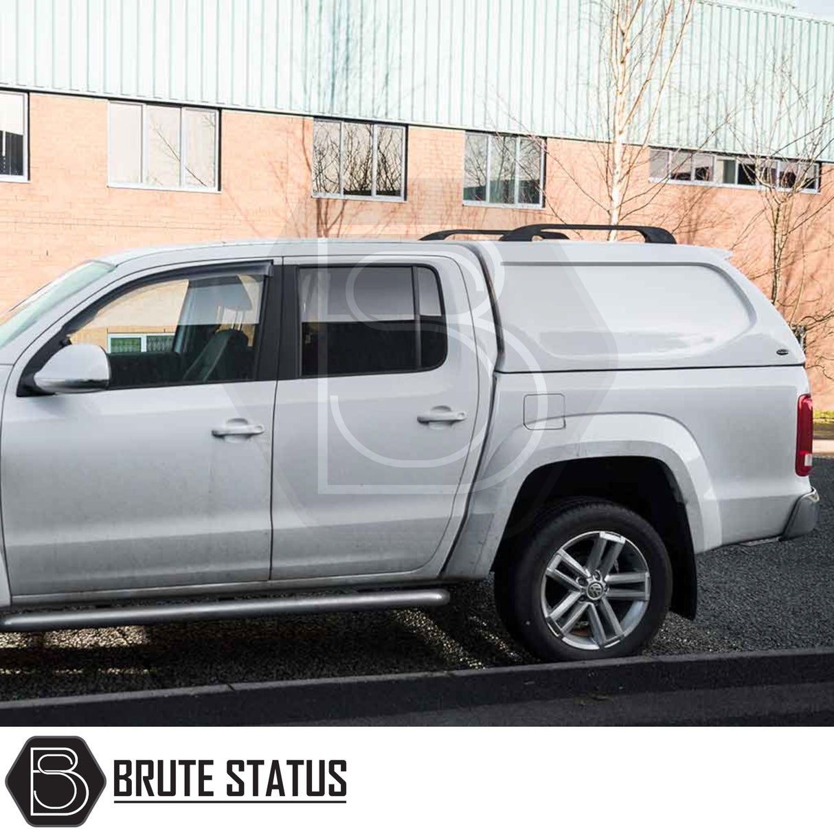 Volkswagen Amarok 2010-2022 Truckman L-Series Hardtop Canopy on silver pickup, enhancing bed security and storage, parked by commercial building, marked with “Brute Status.”