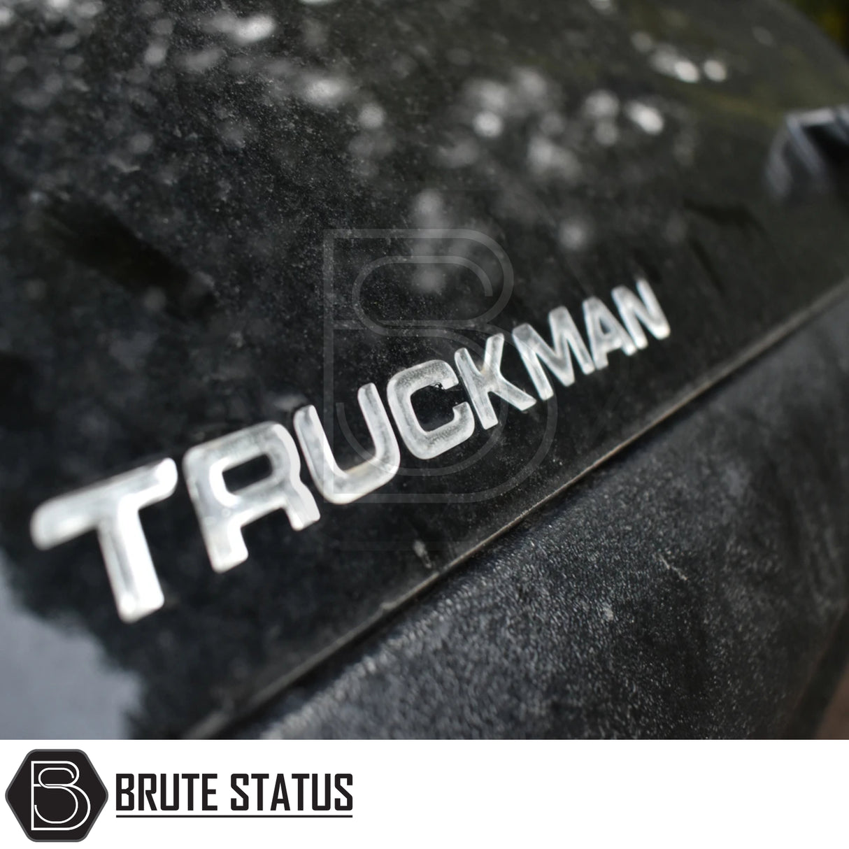 Close-up of metallic TRUCKMAN on black surface, showcasing the Volkswagen Amarok 2023+ Truckman Grand Hardtop Canopy with remote locking and Brute Status logo.
