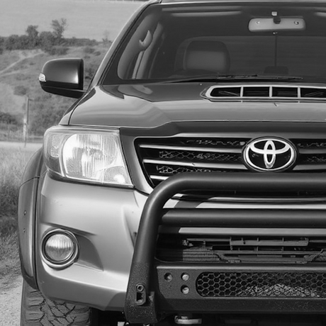 Black and white image of a sport utility vehicle, highlighting its grille and bumper, reflecting Brute Status's focus on unique automotive enhancements.