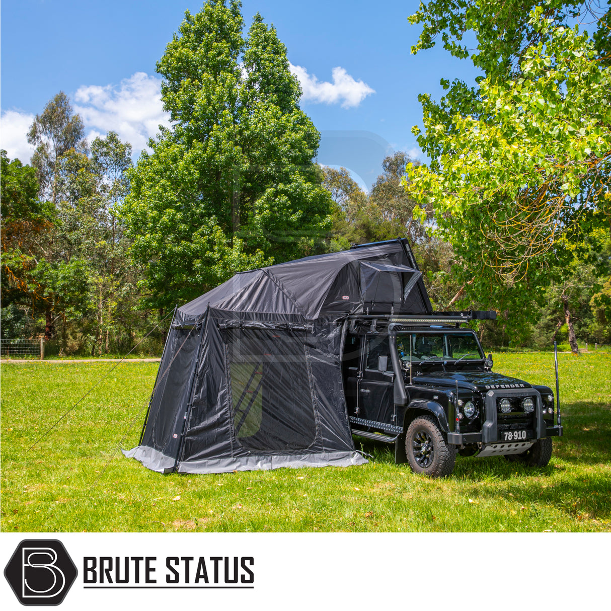 Black Defender-style SUV with ARB Esperance 2.0 Rooftop Tent and Annex Room, showcasing camping setup with awning under trees, branded by Brute Status.