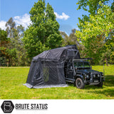 Black Defender-style SUV with ARB Esperance 2.0 Rooftop Tent and Annex Room, showcasing camping setup with awning under trees, branded by Brute Status.