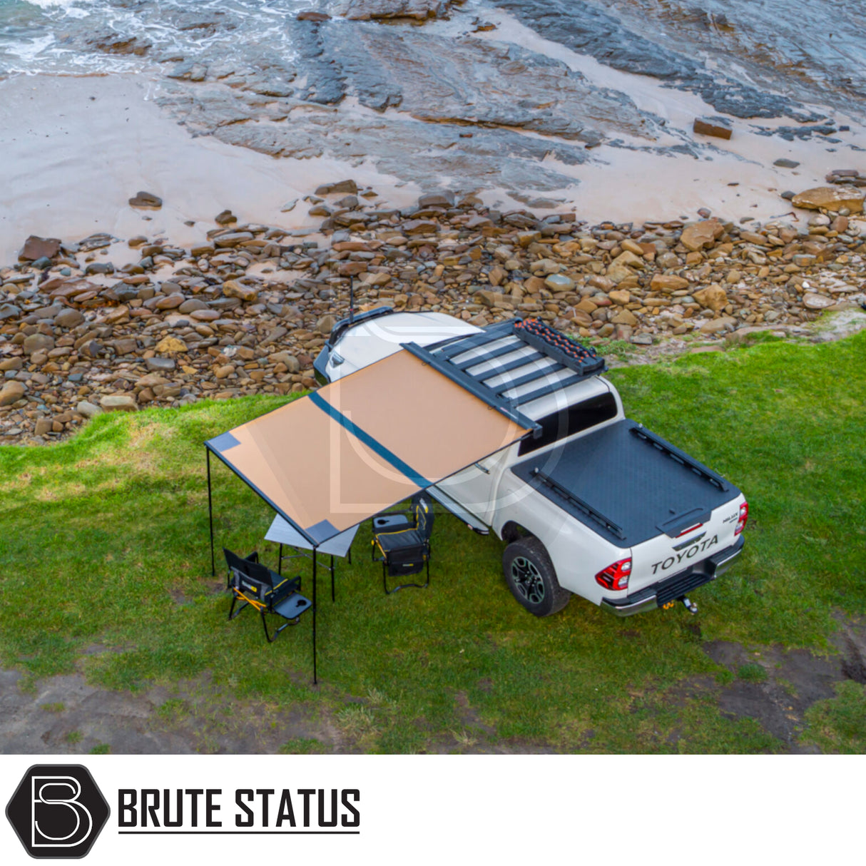 Toyota truck with ARB Aluminium Case Black Awning & LED Light Kit deployed, featuring camping setup by a shoreline.