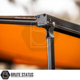 Close-up of ARB Awning Alcove's black aluminum frame, plastic bracket with logo, and orange fabric, showcasing its robust design for versatile outdoor protection.