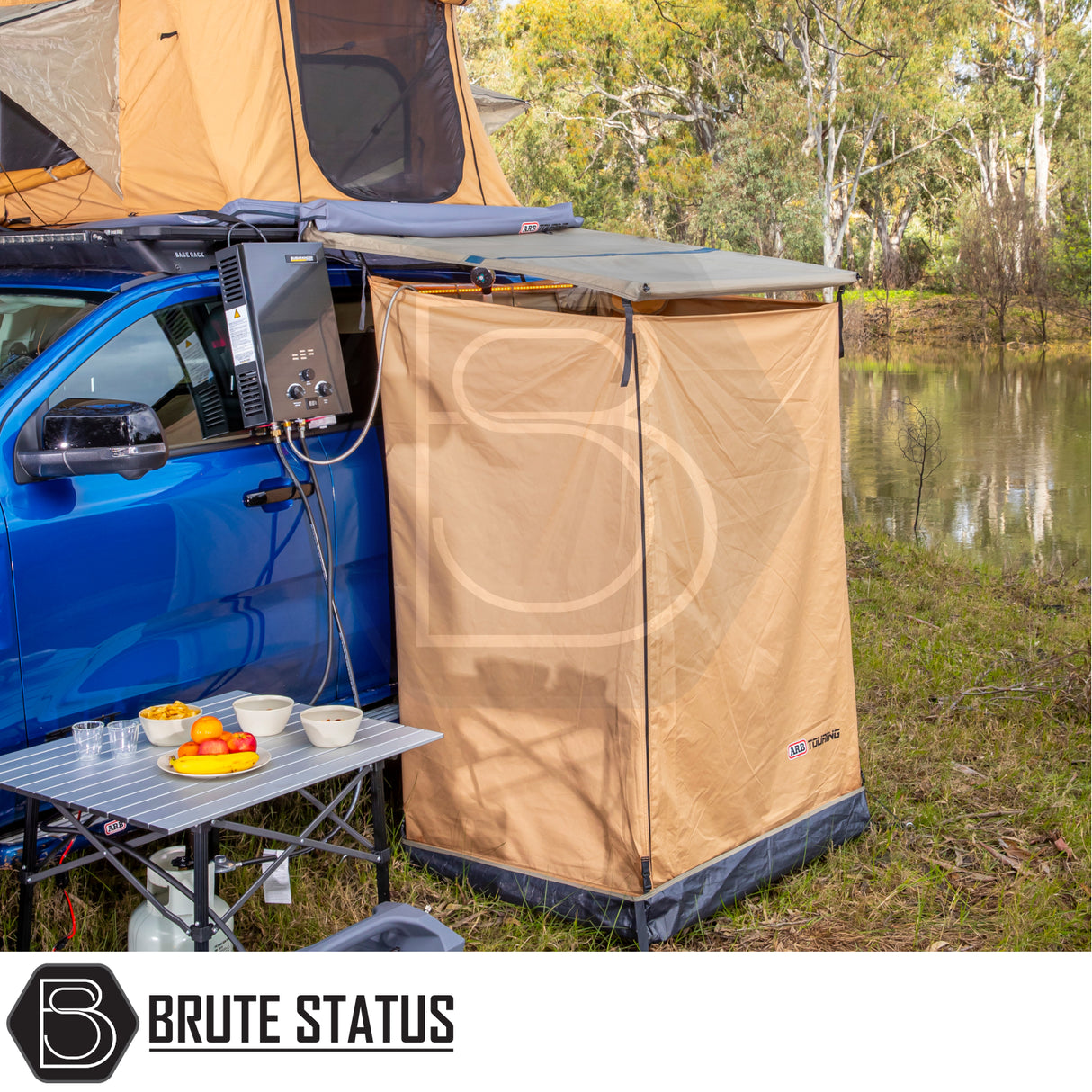 Riverside camping setup with ARB Ensuite Room & Instant Shower Tent attached to a blue 4×4 ute, showcasing a private outdoor shower solution.