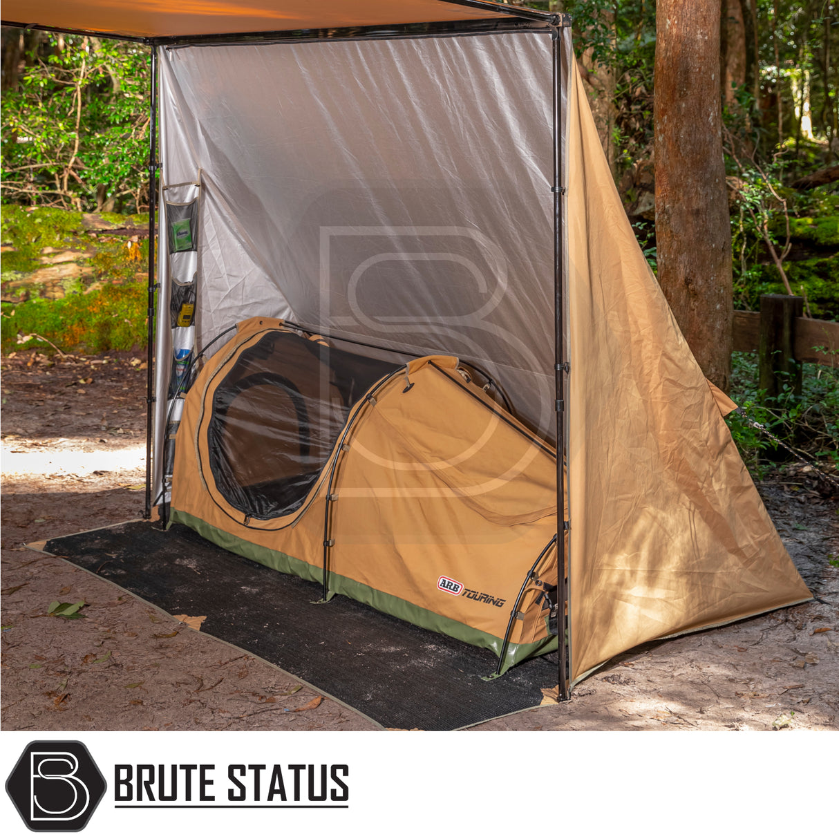 ARB PVC Case Awning & LED Light Kit set up on a vehicle in a wooded campsite, showcasing its protective casing and dual-colour LED lighting feature.