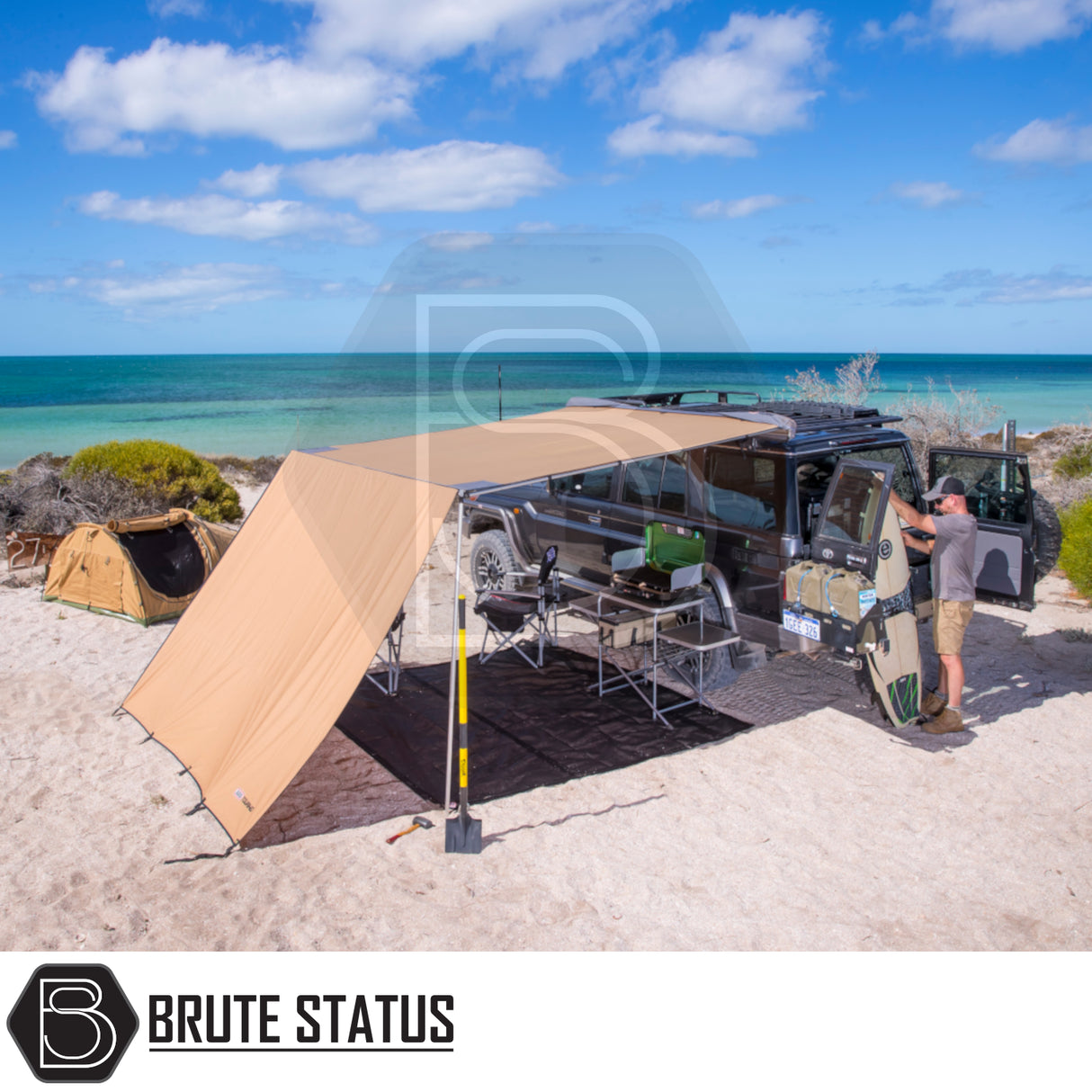 Black 4×4 with ARB Aluminium Case Black Awning & LED Light Kit extends over camp setup on a sandy beach by the ocean.