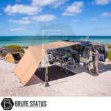 Black 4×4 with ARB Aluminium Case Black Awning & LED Light Kit extends over camp setup on a sandy beach by the ocean.