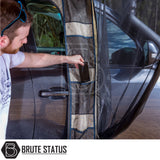 Man placing phone in mesh pocket of Brute Status SUV bug-net curtain, part of ARB PVC Case Awning & LED Light Kit, attached to open vehicle door.