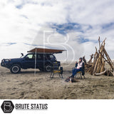 ARB Awning 2m x 2.5m extends from SUV, providing shade over camp chairs at beach campsite, showcasing easy setup and durability for outdoor adventures.