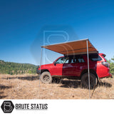 Red off-road SUV with ARB Awning 2m x 2.5m deployed on hillside, showcasing convenient outdoor shelter and Brute Status branding.
