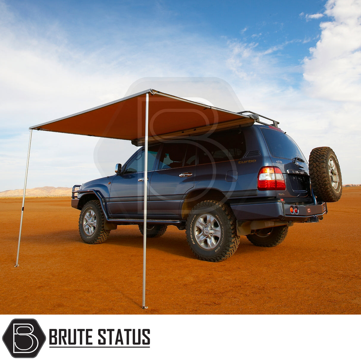 ARB Awning 2m x 2.5m on a 4x4 SUV in desert, creating shaded area with telescopic poles. Ideal for outdoor adventures. Includes Brute Status logo.