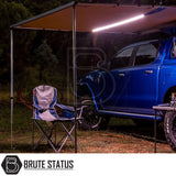 Blue 4x4 pickup with ARB Awning Alcove and integrated LED light, creating a sheltered space with camp chair and table, ideal for versatile outdoor protection.