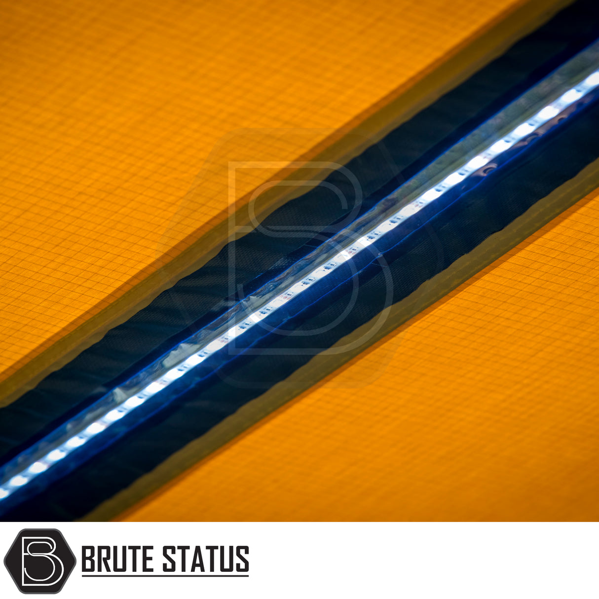 Close-up of ARB PVC Case Awning & LED Light Kit, showcasing white LED strip in black trim on orange ripstop fabric, featuring Brute Status logo.