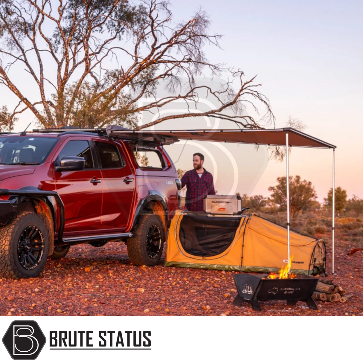 ARB PVC Case Awning & LED Light Kit with extended awning on red pickup, shading a tent and camp kitchen in a desert sunset scene.