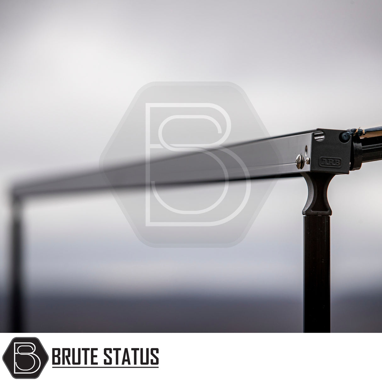 Close-up of ARB Aluminium Case Silver or Black Awning & LED Light Kit, showcasing black anodized aluminum cross-bar, vertical post, and ARB-branded clamp, part of Brute Status off-road hardware.