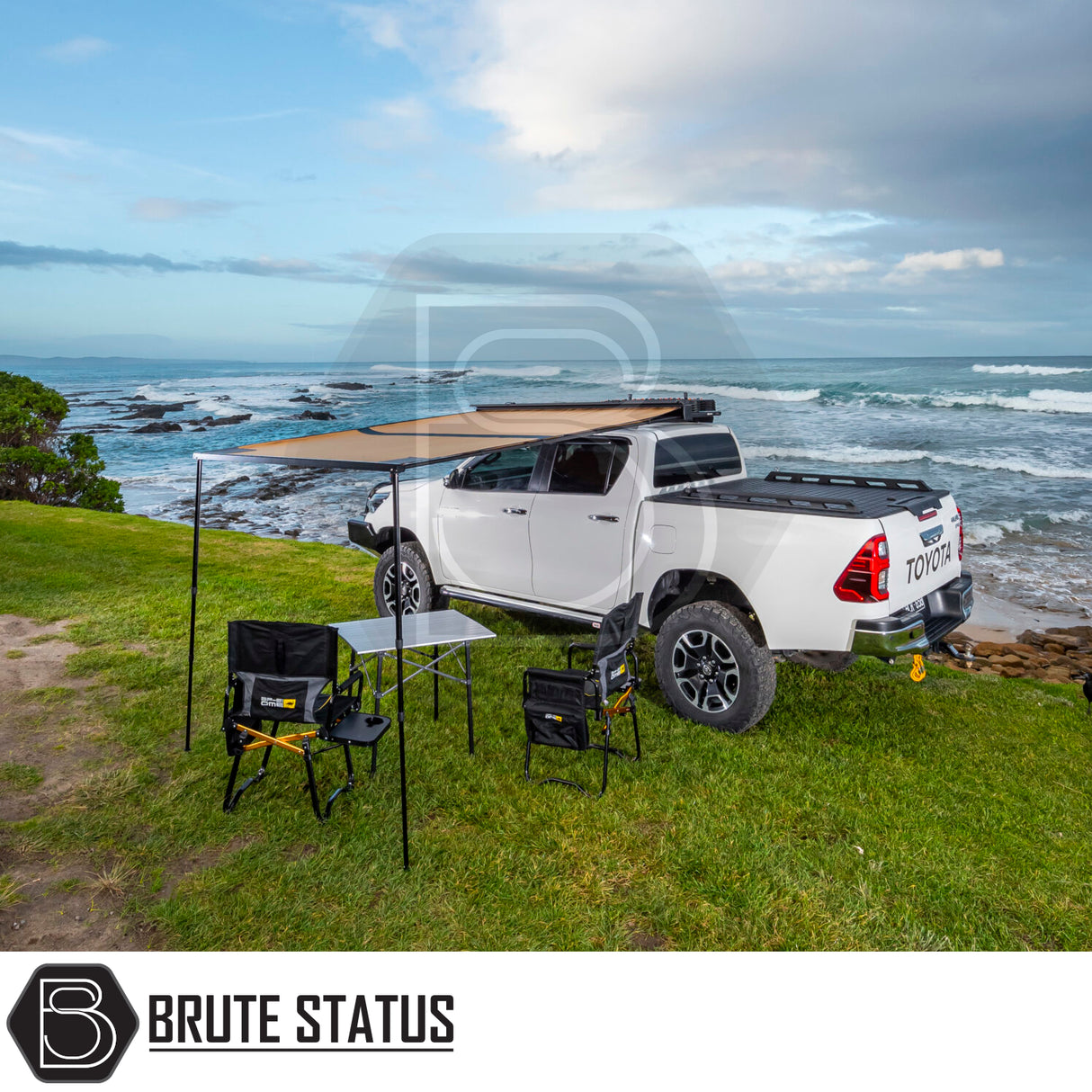 Toyota pickup with ARB Aluminium Case Silver Awning & LED Light Kit, set up on a coastal bluff. Awning extended over table and chairs, ocean view.