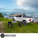 Toyota pickup with ARB Aluminium Case Silver Awning & LED Light Kit, set up on a coastal bluff. Awning extended over table and chairs, ocean view.