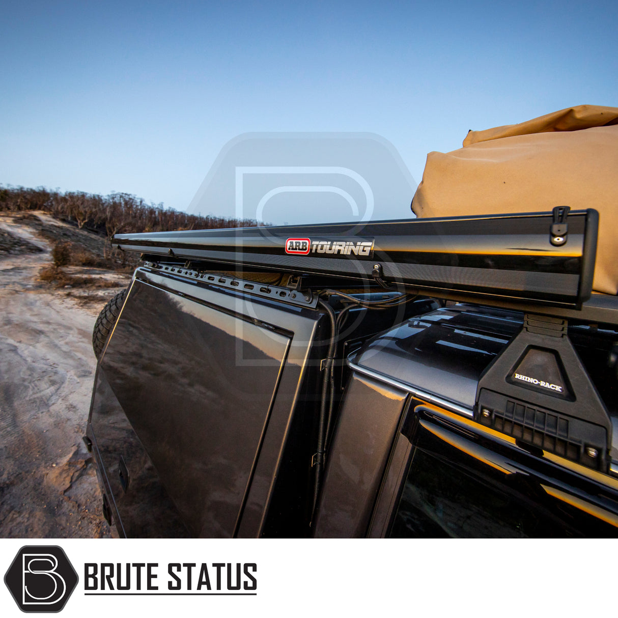 4×4 rig with ARB Aluminium Case Awning & LED Light Kit, folded on Rhino-Rack, parked on sandy trail at dusk; Brute Status logo visible.