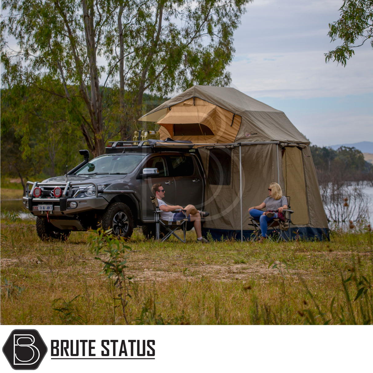 ARB Simpson III Rooftop Tent & Annex set up on pickup truck by lakeside, featuring tent with annex, camping chairs, and scenic water backdrop.