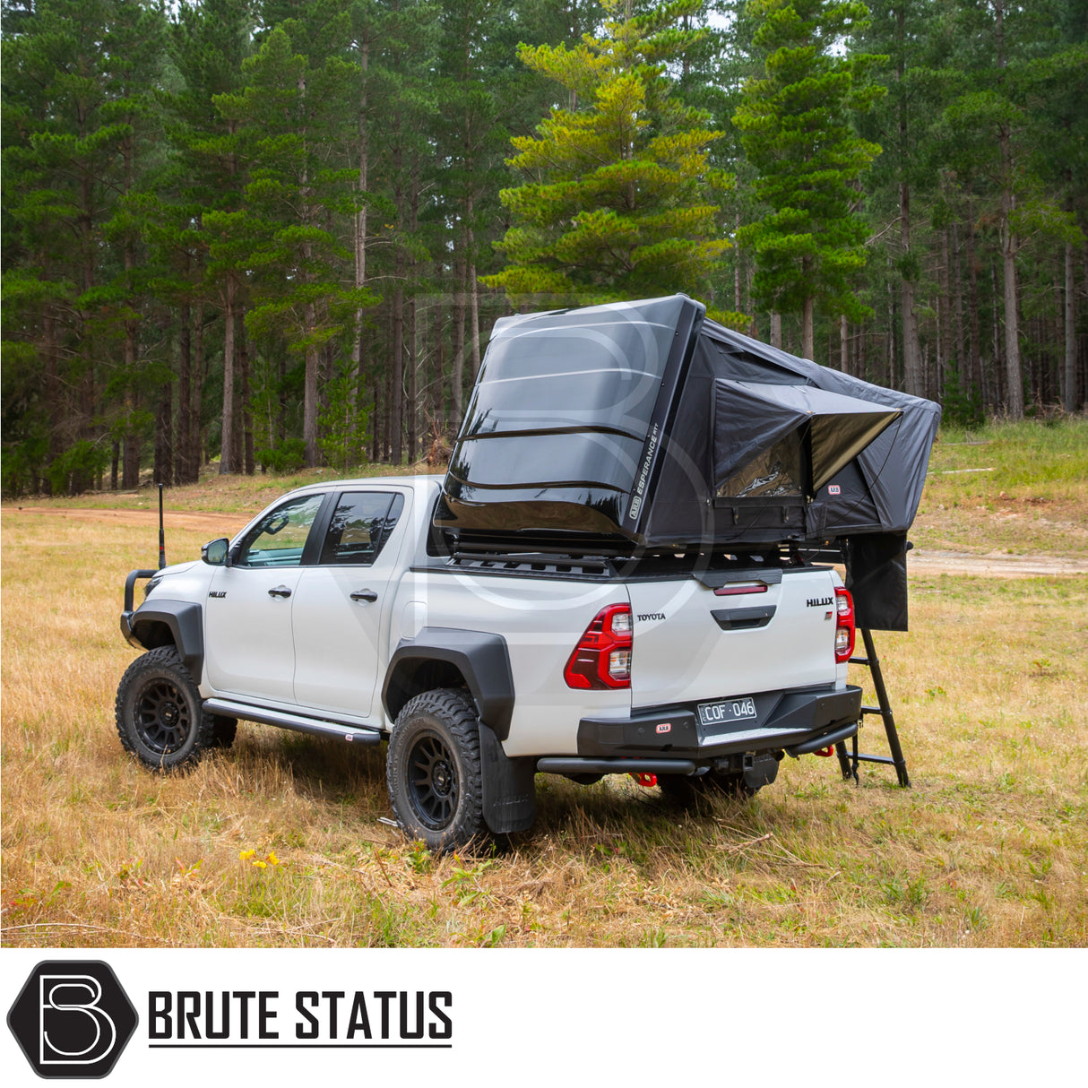 Toyota Hilux with ARB Esperance 2.0 Rooftop Tent, off-road ready, featuring a hard shell, rooftop tent setup in a forest clearing, showcasing Brute Status enhancements.
