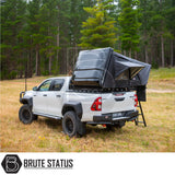 Toyota Hilux with ARB Esperance 2.0 Rooftop Tent, off-road ready, featuring a hard shell, rooftop tent setup in a forest clearing, showcasing Brute Status enhancements.