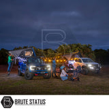 Camping scene with two pickup trucks, each fitted with ARB Esperance 2.0 Rooftop Tent Hard Shells, string lights, and a portable fire pit.
