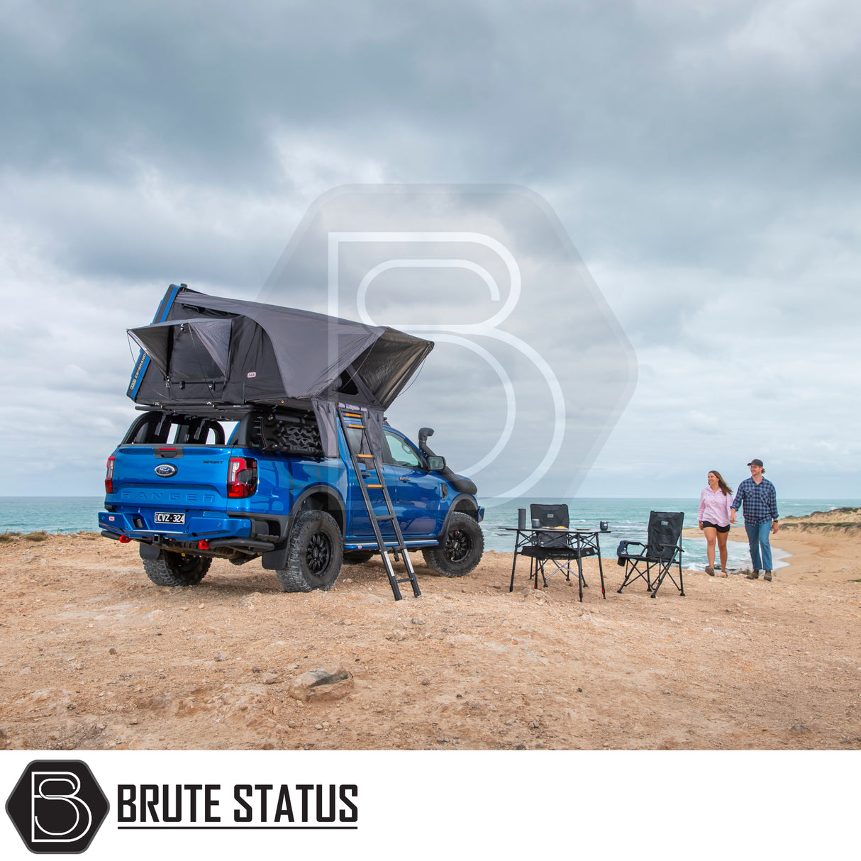 Rooftop tent on a Ford Ranger at a beach, showcasing the ARB Esperance 2.0 Rooftop Tent's setup with ladder and camping gear, under Brute Status branding.