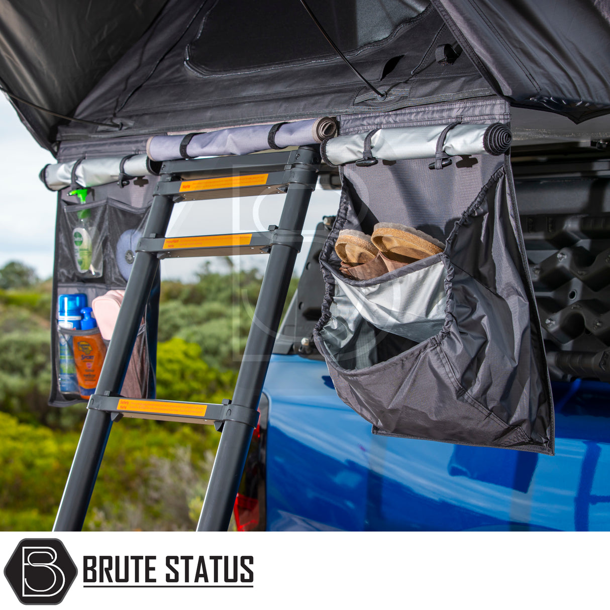 ARB Esperance 2.0 Rooftop Tent on blue pickup, featuring a telescoping ladder and organizer pouches with camp shoes and toiletries, highlighting overland-camping convenience.